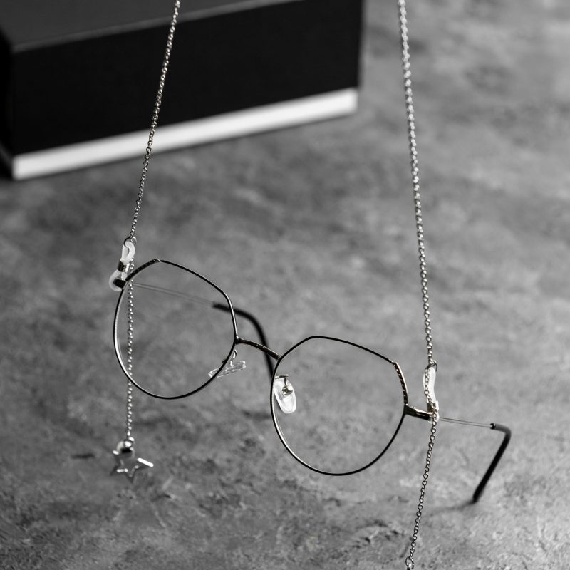 uma-vista-frontal-de-oculos-de-sol-opticos-na-mesa-cinza-com-correntes-de-prata